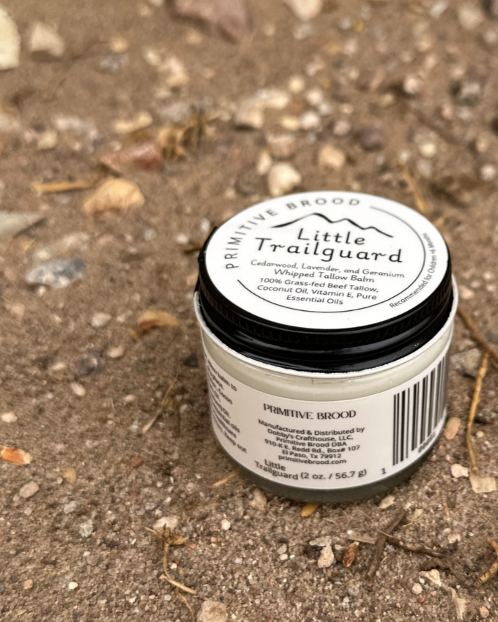 Little Trailguard 2 ounce jar sitting on a trail besides some rocks in the desert. 